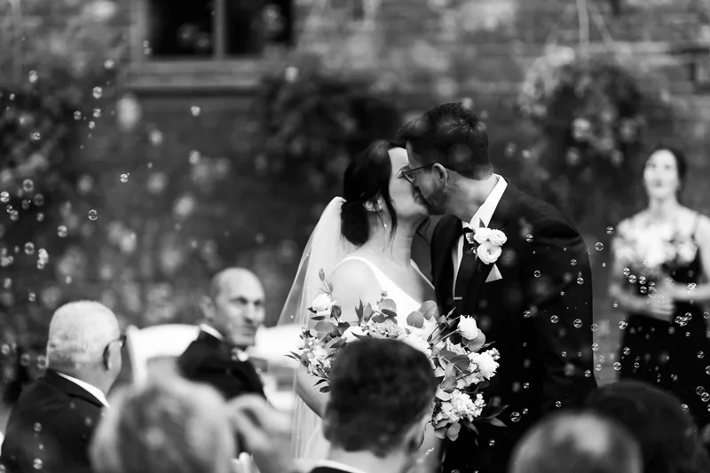 Newlyweds kissing during their ceremony as bubbles float around them